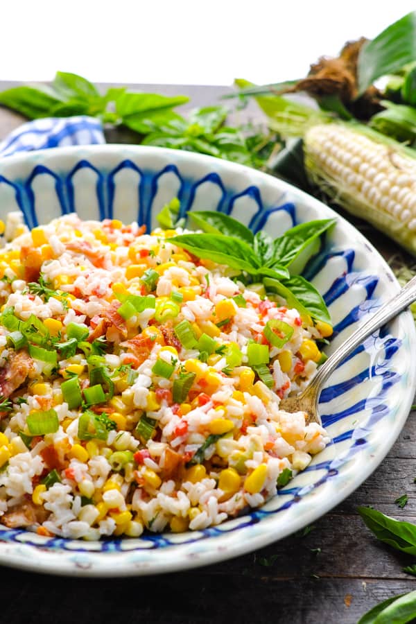 Close up front shot of a bowl of cold rice salad with corn and pimentos