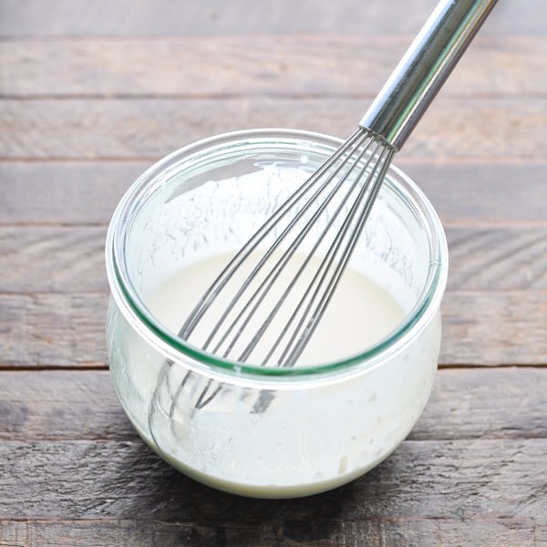 Buttermilk dressing in a glass bowl with whisk