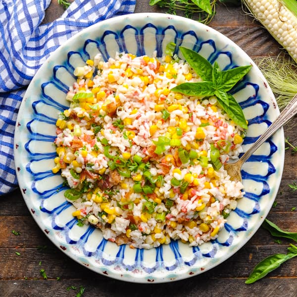 Square overhead image of southern rice salad with fresh herbs on a wooden table