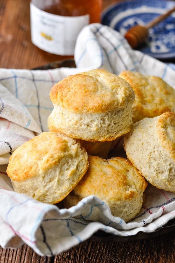 Front shot of a basket of buttermilk biscuits with a check towel