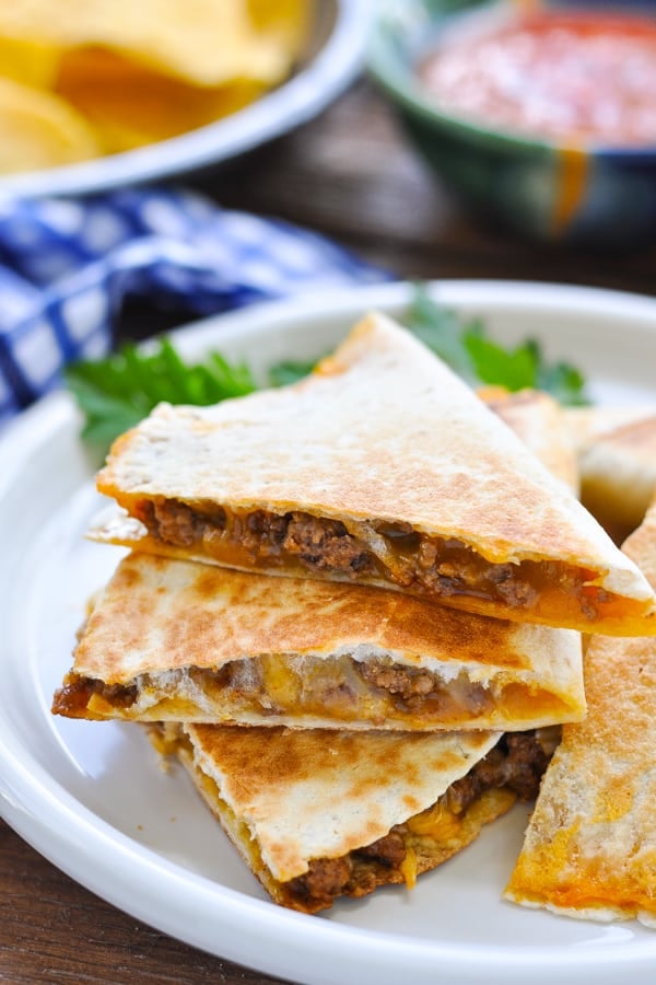 Stack of cheesy taco quesadillas on a white plate