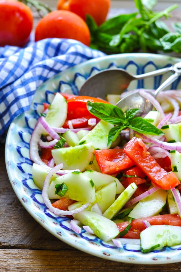 Bowl of tomato cucumber onion salad with fresh basil and apple cider vinegar