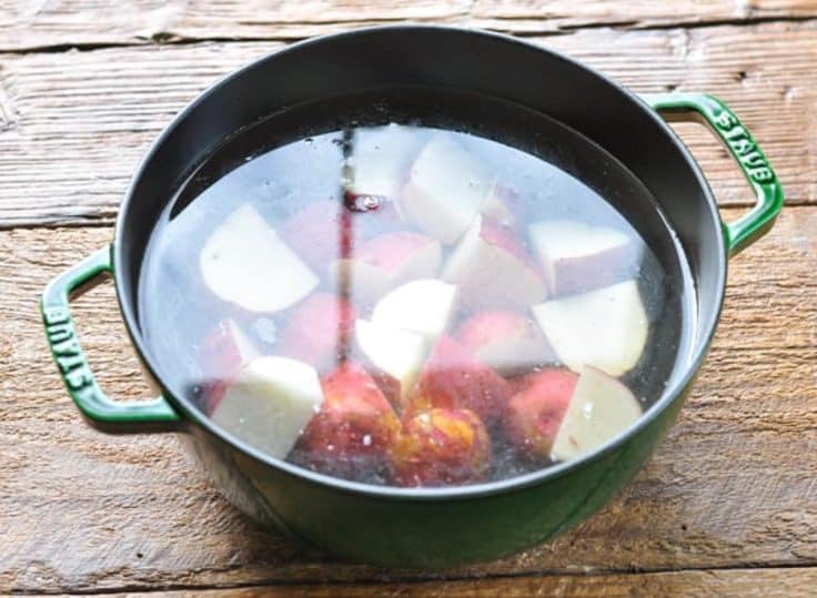 Pot of red potatoes with skin in water.