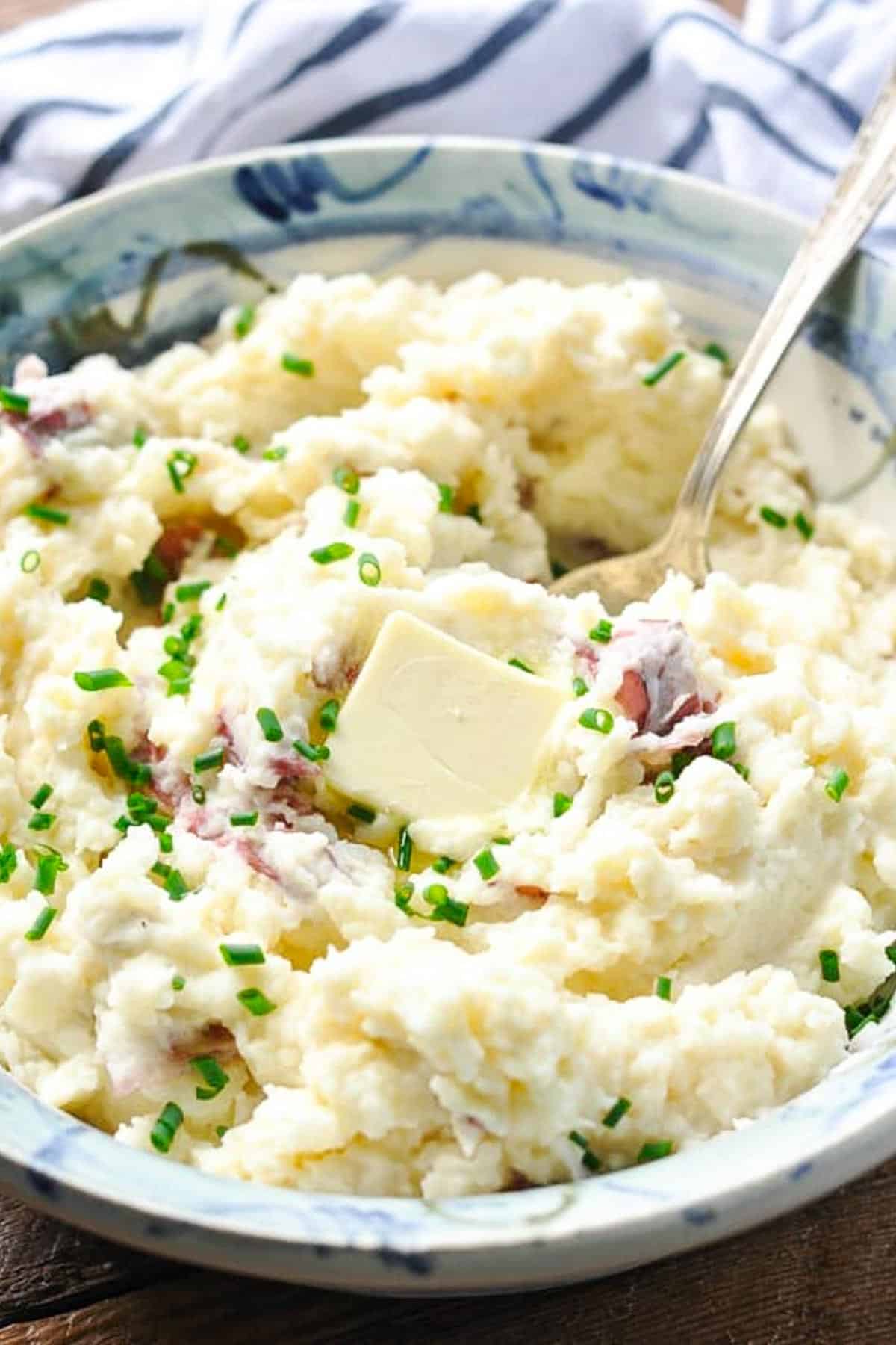 Close up side shot of easy red skin mashed potatoes with butter and chives in a bowl.