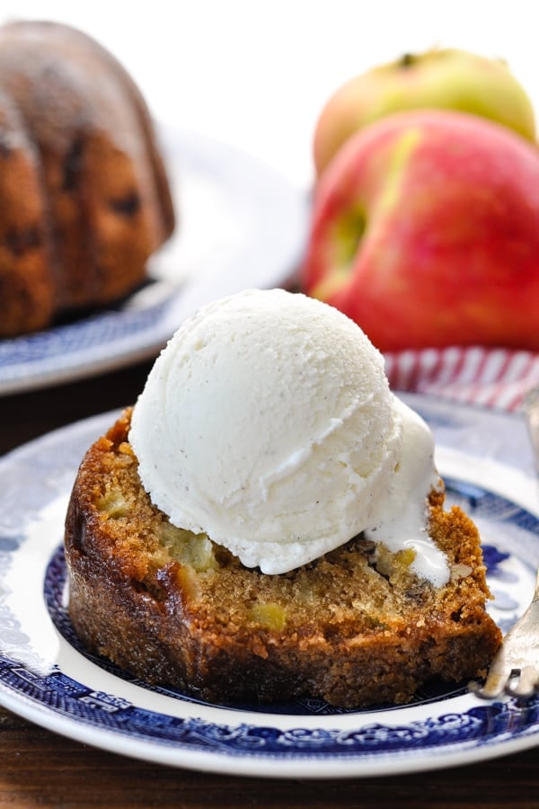 Close up front shot of a slice of old fashioned fresh apple cake with a scoop of vanilla ice cream on top