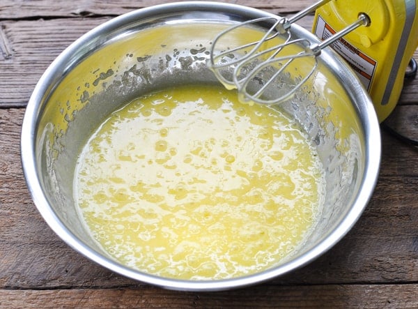 Wet ingredients for apple cake batter in a metal mixing bowl