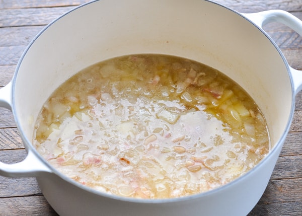 Process shot of making brunswick stew in a white dutch oven