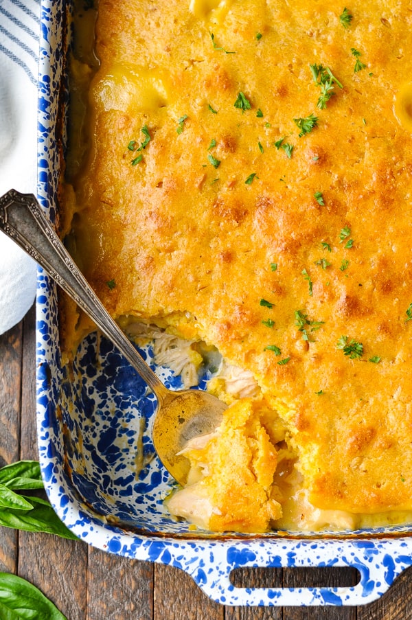 Close overhead image of chicken and jiffy cornbread casserole in a baking dish with serving spoon