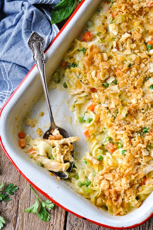 Overhead shot of cheesy chicken noodle casserole in a white baking dish on a wooden table