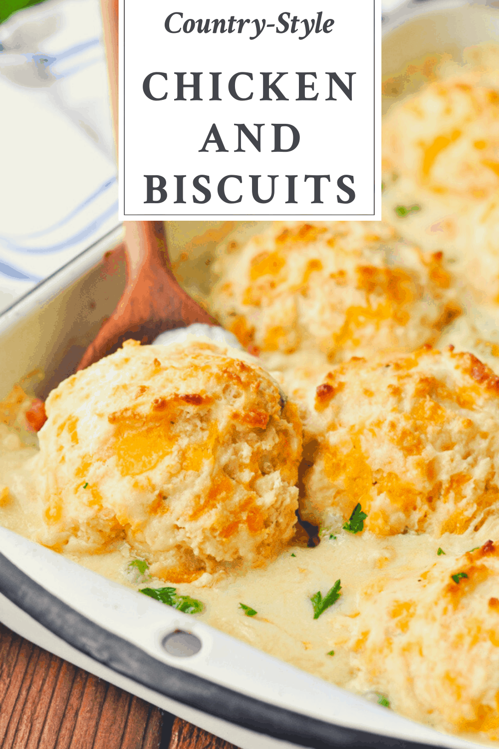 Close up front shot of a wooden spoon scooping up chicken and biscuits with a text title box at the top