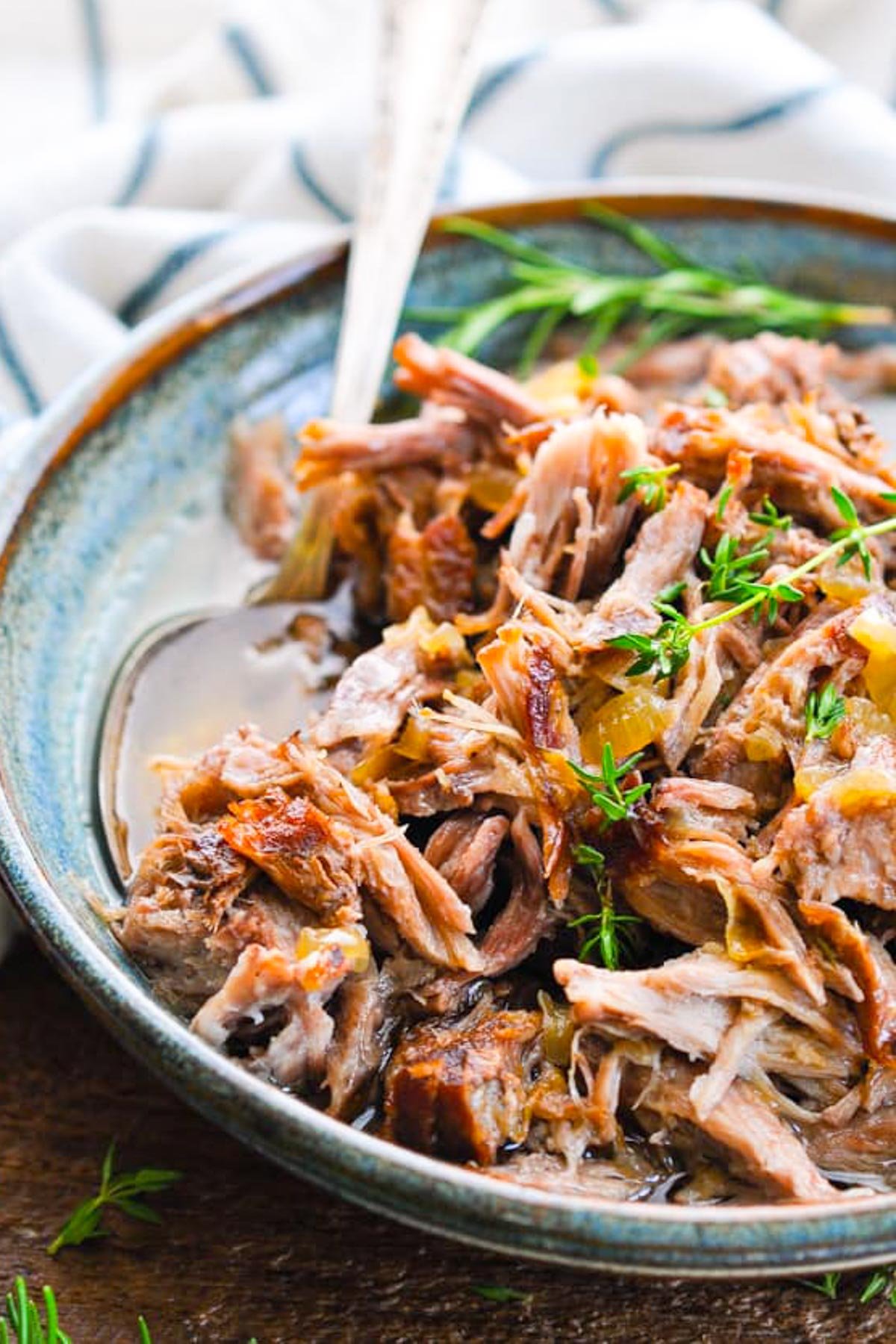 Close up shot of a spoon in a bowl of braised pulled pork.