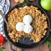 Square overhead shot of apple crisp in a cast iron skillet with vanilla ice cream on top.