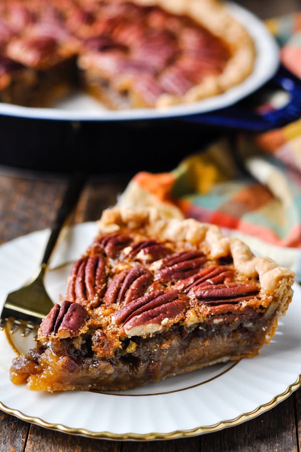 An easy pecan pie recipe sliced and served on a white plate with gold trim