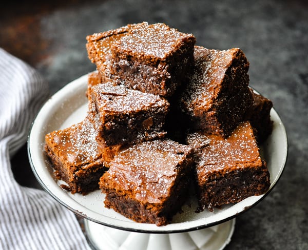Horizontal image of fudgy brownies dusted with powdered sugar