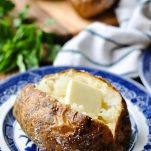 Open baked potato with salt and butter on a blue and white plate