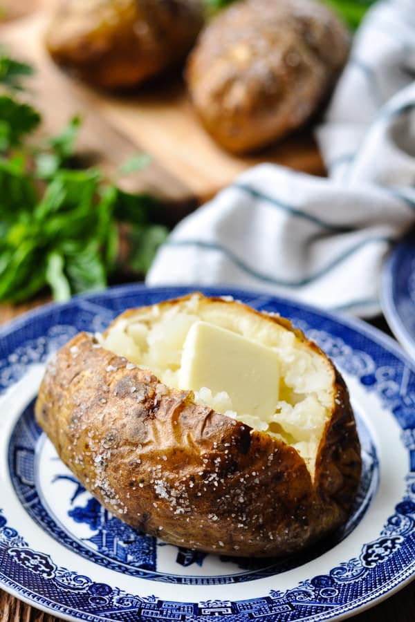 Open baked potato with salt and butter on a blue and white plate