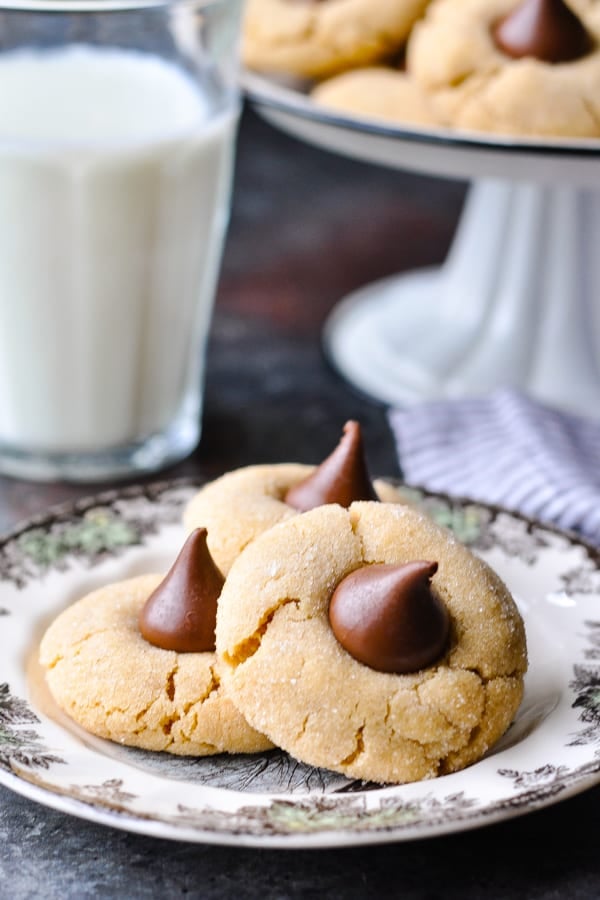 Close up side shot of three peanut butter blossom cookies on a small plate