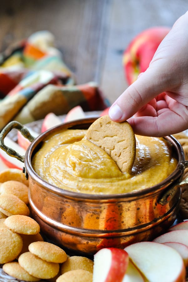 Child dipping a gingersnap cookie in pumpkin dip