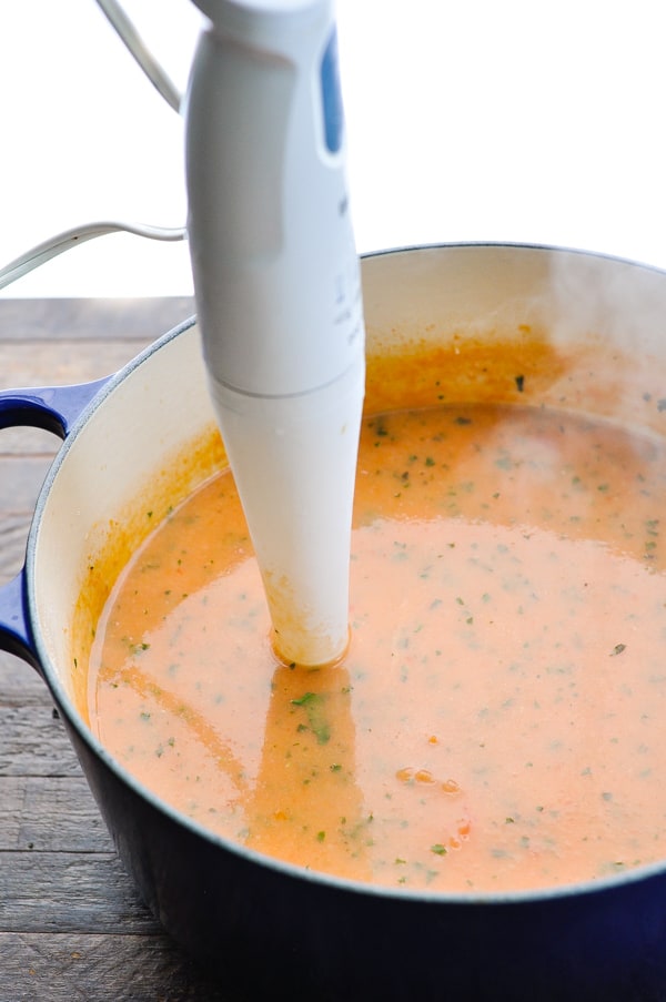 Using an immersion blender to puree a pot of tomato basil soup