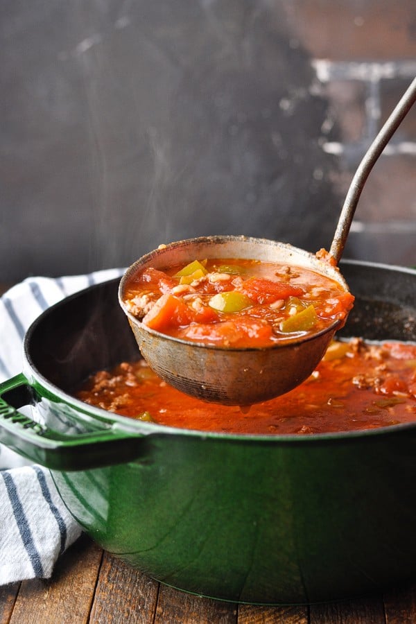 Side shot of a ladle full of steaming hot stuffed bell pepper soup