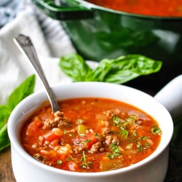 Silver spoon in a bowl of stuffed pepper soup with parsley on top