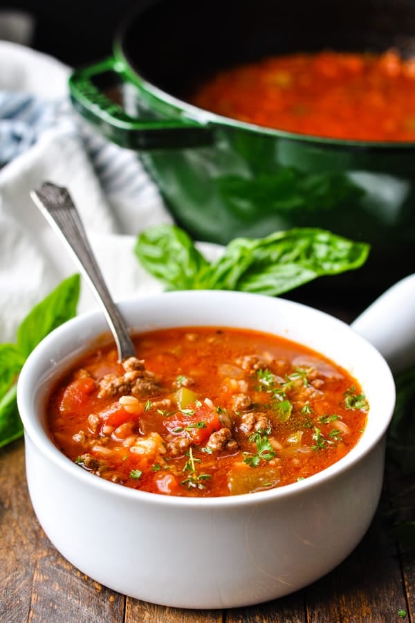 Silver spoon in a bowl of stuffed pepper soup with parsley on top