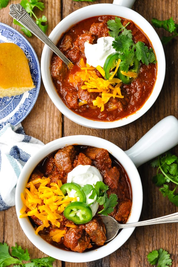 Overhead shot of two bowls of texas chili on a wooden table