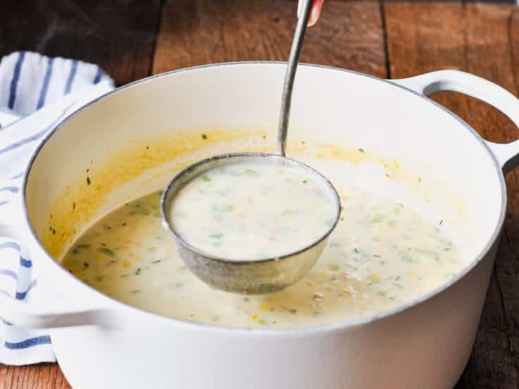 Ladle serving a corn chowder recipe from a Dutch oven.