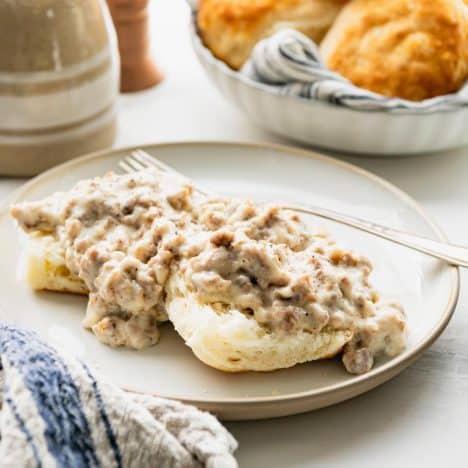 Square side shot of Southern sausage gravy spooned over biscuits.
