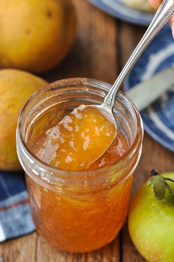 Spoon scooping up spiced pear jam from a mason jar