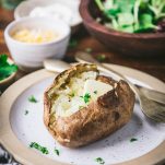 Square featured image of a baked potato on a plate with butter and herbs