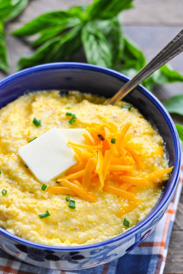 Front shot of a bowl of easy cheese grits on top of a blue white and orange plaid napkin
