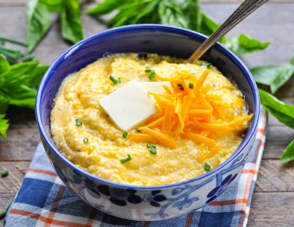 Bowl of homemade cheese grits topped with butter, chives and more cheese