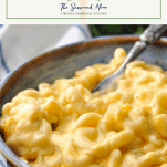 Text title box over a close up shot of a bowl of creamy baked mac and cheese