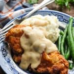 Front shot of fried chicken cutlets on a plate with green beans and mashed potatoes
