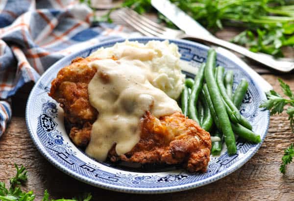Horizontal shot of pan fried chicken cutlets on a plate with gravy