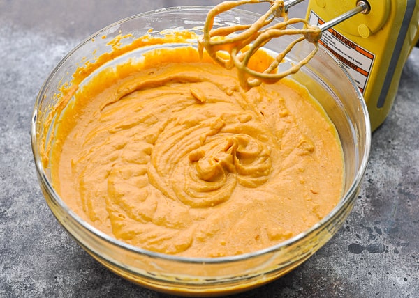 Mixing pumpkin cheesecake filling with a hand mixer