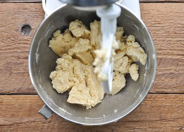An overhead shot of a stand mixer bowl filled with raw shortbread cookie dough.