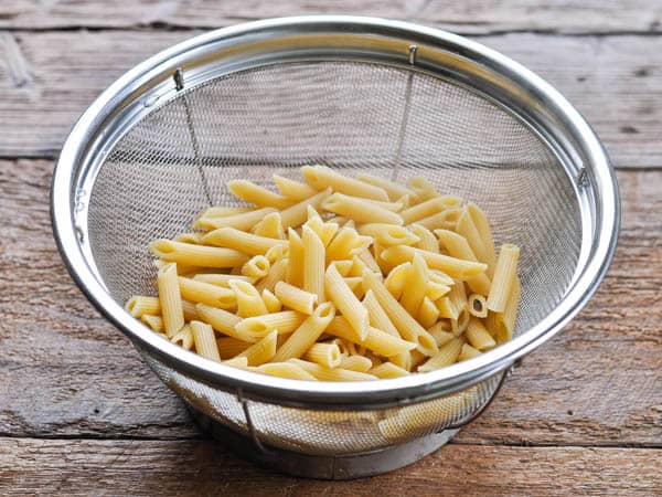 Cooked penne pasta in a colander