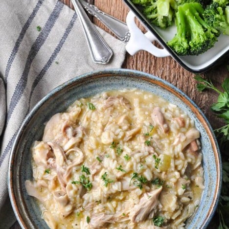 Overhead image of a bowl of slow cooker chicken and rice served with a side of broccoli