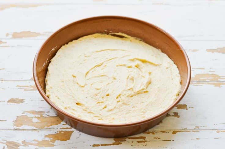 Spreading breakfast cake batter in a round cake pan.