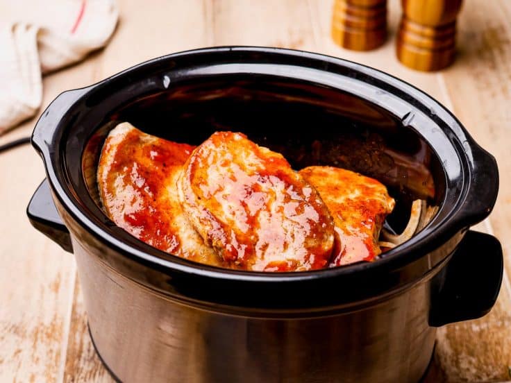 Crock pot smothered pork chops recipe ingredients in a slow cooker before covering and cooking.