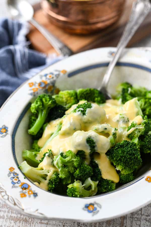 Silver spoon in a serving dish full of broccoli and cheese sauce
