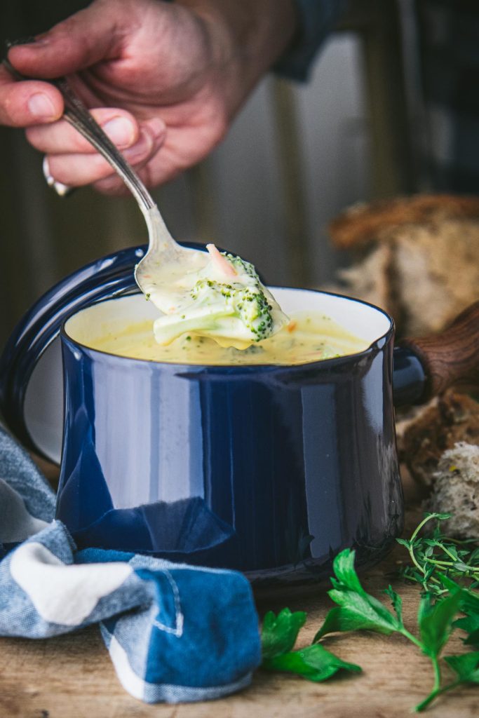 Front shot of spoon scooping up a bite of broccoli and cheese soup