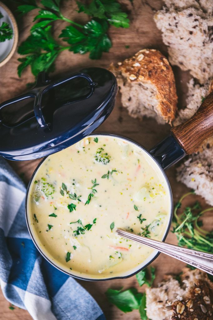 Overhead shot of a spoon in a bowl of broccoli cheese soup with bread