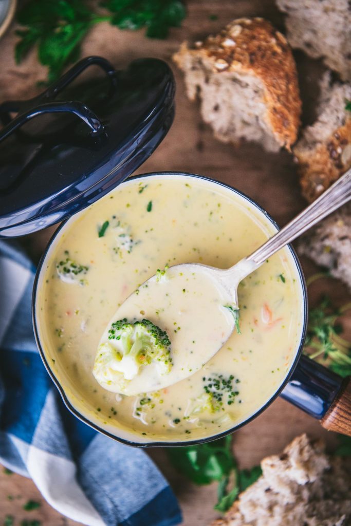 Close overhead shot of a spoon in a bowl of broccoli and cheese soup