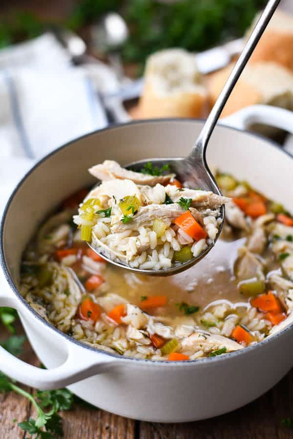 Ladle serving healthy chicken and rice soup from a pot
