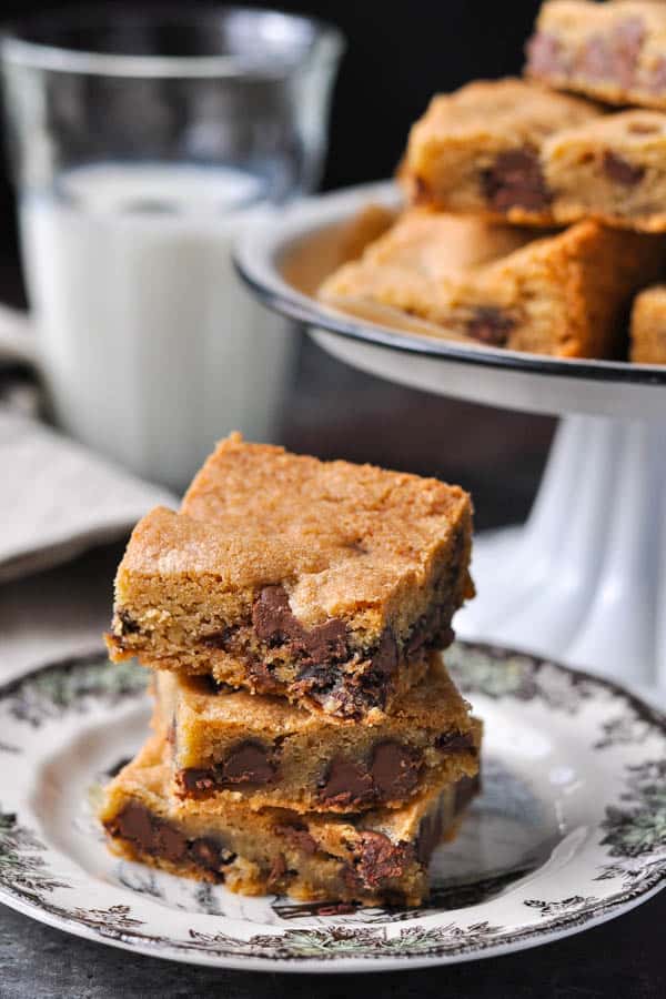 Three easy chocolate chip cookie bars on a plate with milk in the background