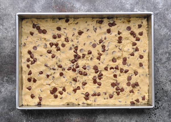 Overhead shot of chocolate chip cookie bar dough in a pan before baking