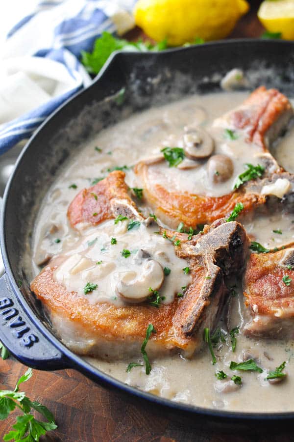 Close side shot of a skillet full of smothered pork chops with cream of mushroom soup
